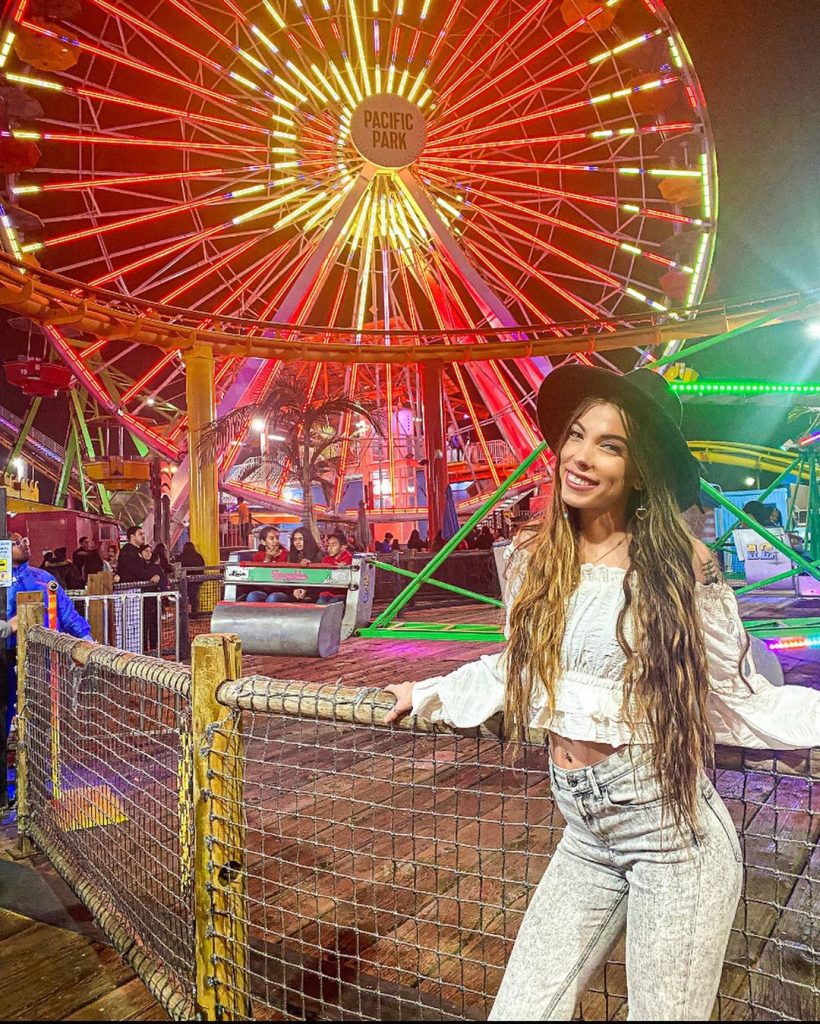 Instagrammer @strictlyphysical standing on the Santa Monica Pier in front of the Pacific Wheel which is bright red for Chinese New Year (2019)