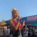 Saweetie in a pink top raps for fans in front of the Pier Gear retail shop at Pacific Park
