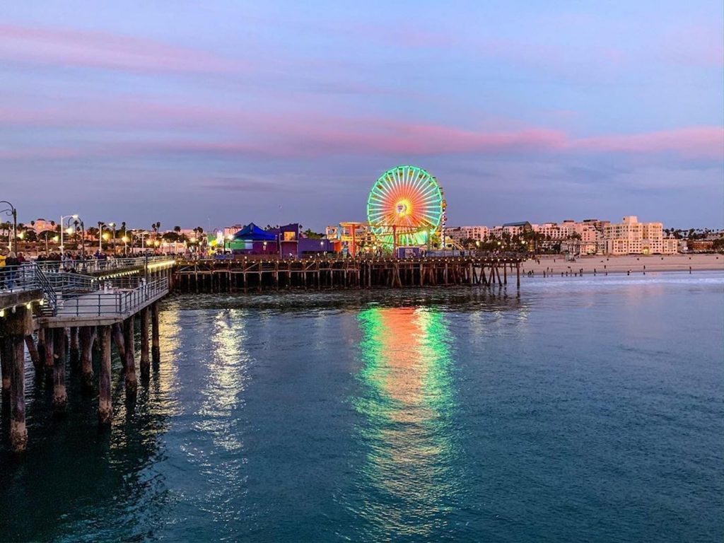 Red, white, and green lights shine on the Ferris wheel at the Santa Monica Pier