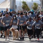 Runners in grey shirts preparing to start the Rick Crocker 5K at the Santa Monica Pier in May 2022
