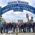 Local leaders and activists pose under the famous Santa Monica Pier sign to comemorate 50 years since they saved the pier from destruction