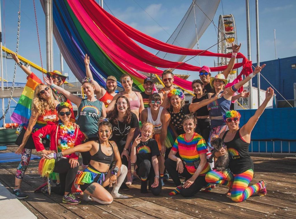 Trapeze School Students wearing brightly-colored rainbow attire in a group photo
