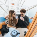 A couple enjoys iced coffee served inside the gondola of the Ferris wheel on the Santa Monica Pier