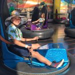 A young guest in a Hawaiian-style shirt rides a bumper car at Pacific Park